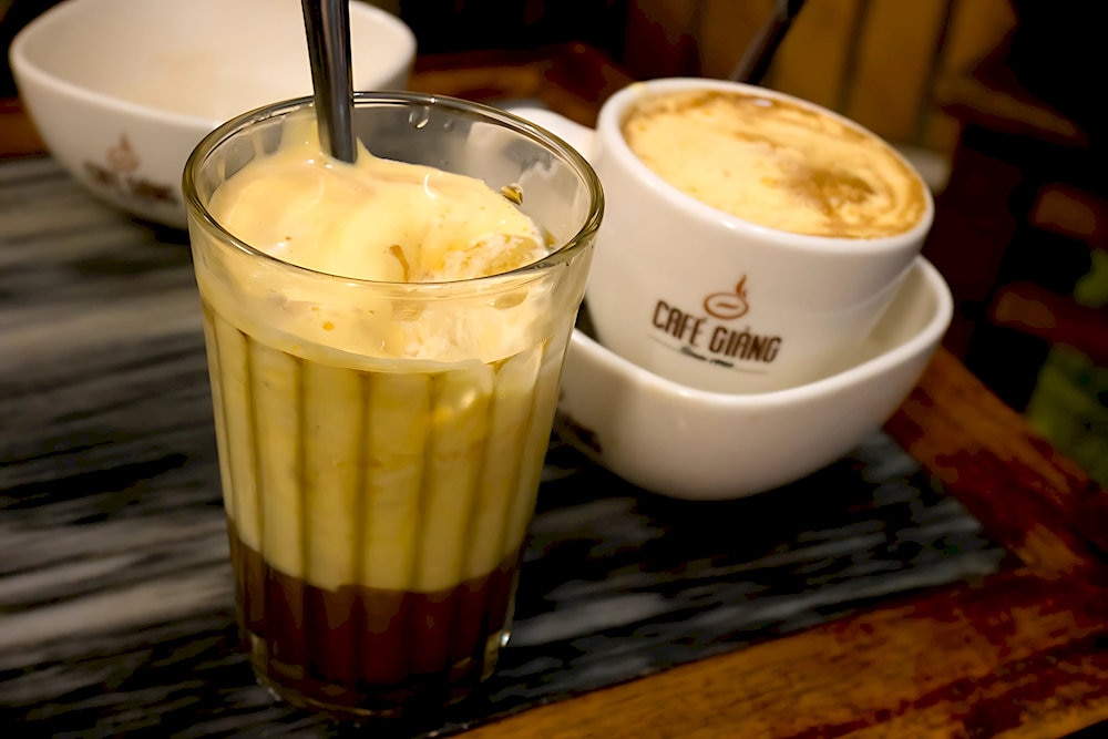 Hot egg coffee stays warm in a water bath, while the iced version is served chilled in a single glass